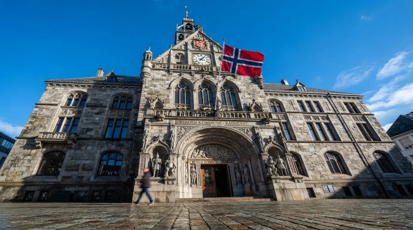 Ett gammalt stadshus i sten fotograferat underifrån mot en klarblå himmel, med den svenska flaggan som fladdrar ovanför entrén.